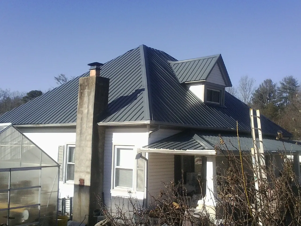Dark blue standing seam metal roof on a white farmhouse with dormer — Slate & Tile Roof Repair by Roofing Brothers in Westtown