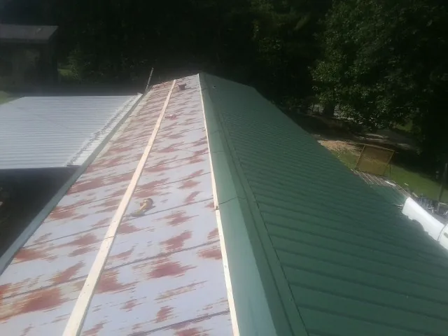 Old rusted panels beside newly installed green metal roofing — Wind Damage Roof Repair by Roofing Brothers in Westtown
