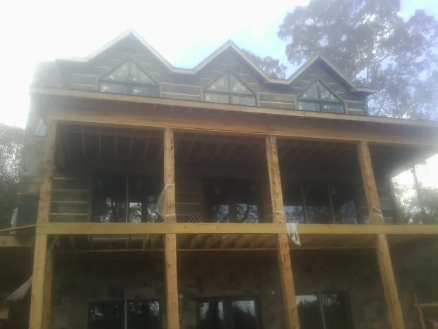 Dormers and porch framing on a large log home under construction — Roof Coating work by our crew in Westtown