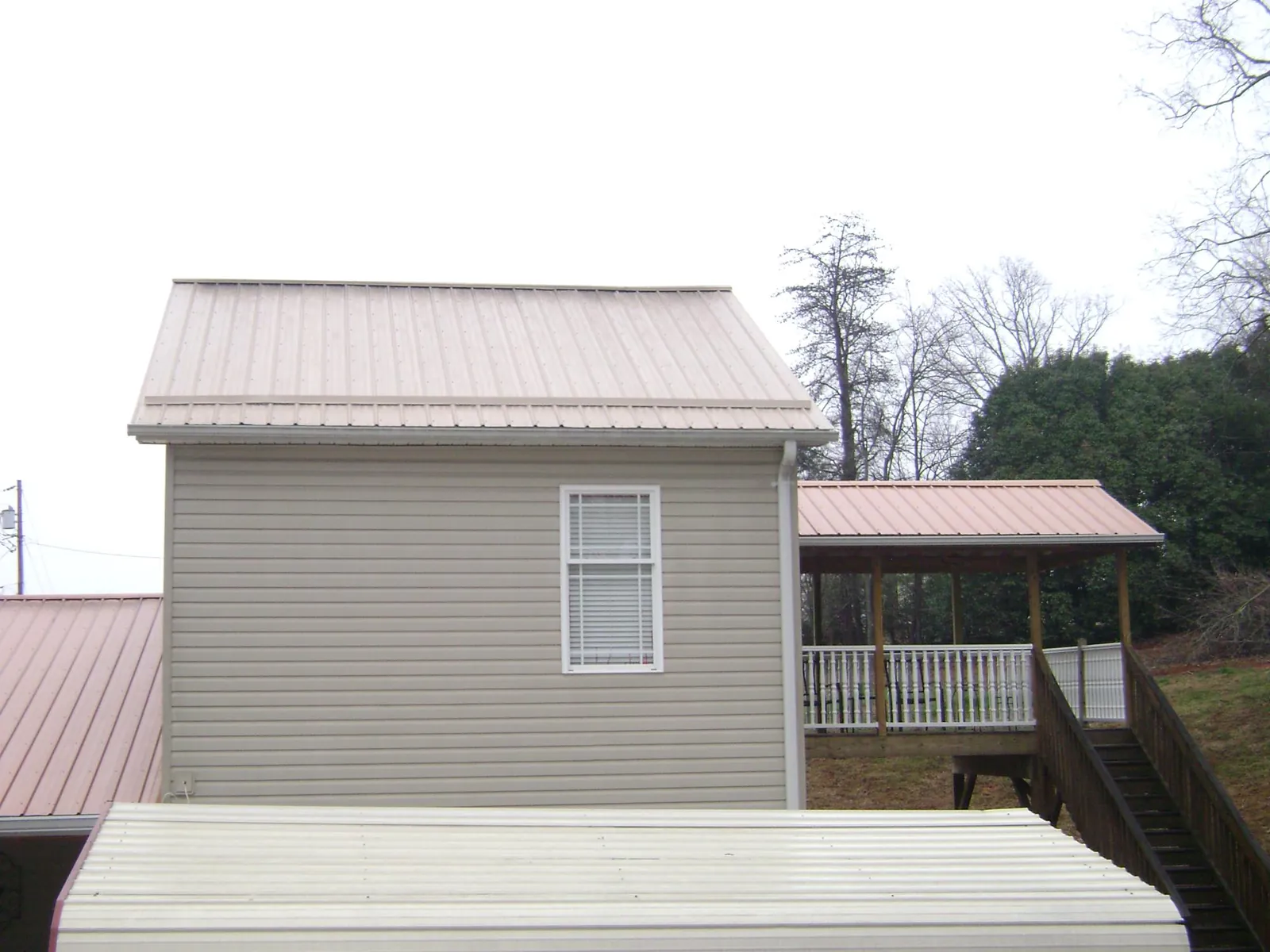 Tan metal roofs on a two story addition and attached porch, from a Roof Replacement job in Westtown