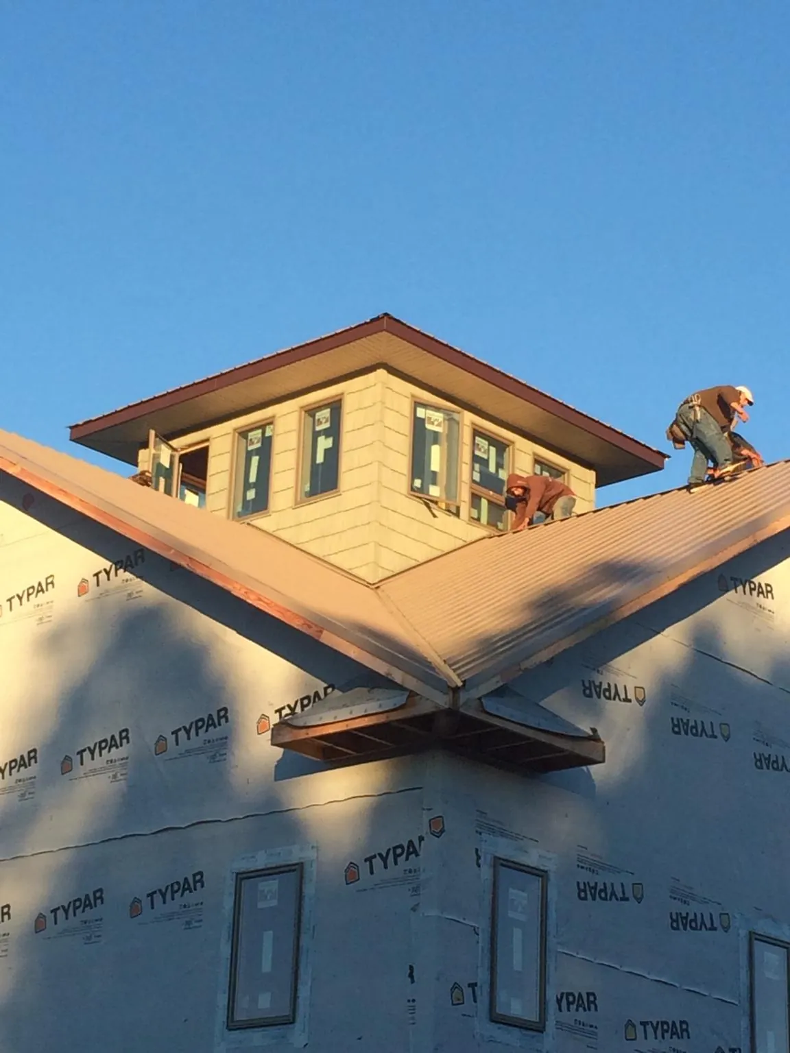 Roofers working around a rooftop cupola on a new metal roof at sunset — Roof Waterproofing in Westtown by Roofing Brothers